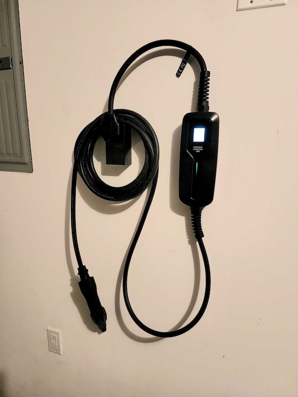 A portable charging station with a cable connected to a wall socket. - Idyllic carriage house private 2 car garage W/D (Newark)