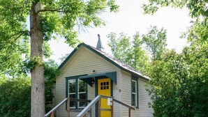 Una piccola casa a un solo piano con una porta gialla e un piccolo portico.