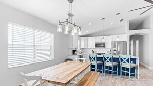 A modern kitchen with white cabinets, a wooden dining table, and blue chairs.