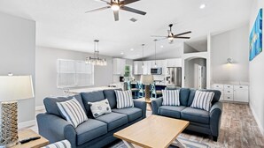 A modern living room with two sofas, a coffee table, and a kitchen in the background.