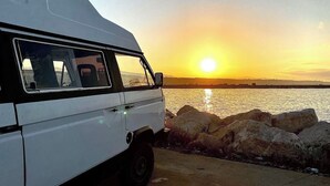 Een witte bestelwagen geparkeerd aan een haven bij zonsondergang.