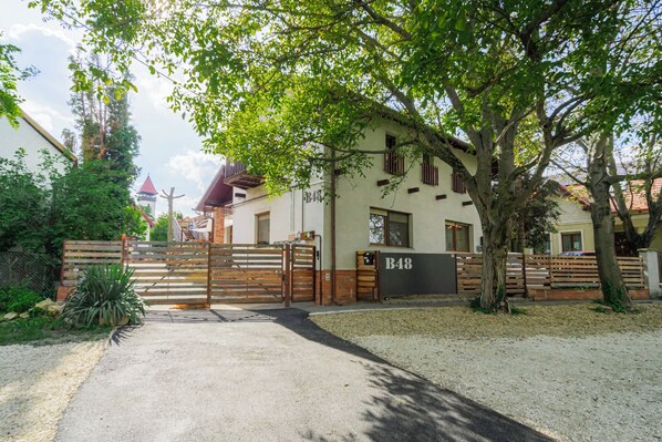 A gated property with a white building, a wooden gate, and a tree in front. - Spacious vacation apartment also for families. (Törökbálint)