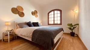 A bedroom with a bed, bedside table, lamp, and a window with a view. - Apartment Alegría | Stylish accommodation right by the sea (Playa Honda)