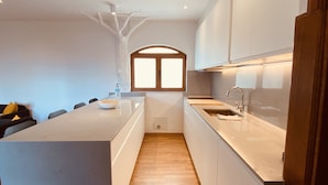 A modern kitchen with a central island, wooden flooring, and white cabinetry. - Apartment Alegría | Stylish accommodation right by the sea (Playa Honda)