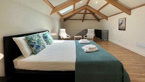 Un dormitorio con cama, dos sillas, una ventana y un tragaluz.