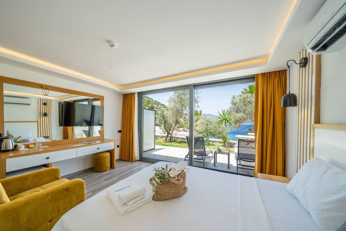 A hotel room with a bed, a desk, a chair, a large window, and a view of the outdoors.