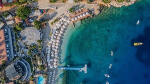 An aerial view of a coastal resort with a marina, beach umbrellas, and a pool. - Kalkan Beach Park Hotel (Kas)