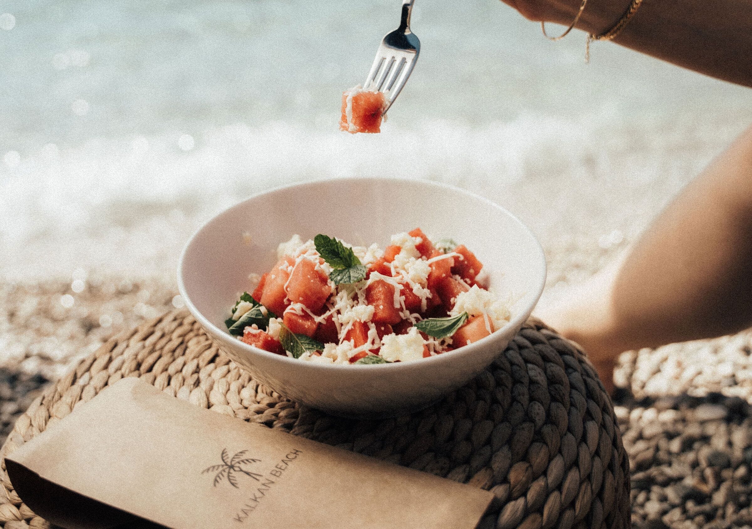 A bowl of food on a woven mat with a napkin beside it.