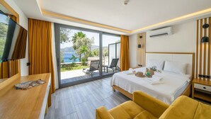 A modern hotel room with a bed, a TV, a desk, and a view of the outdoors. - Kalkan Beach Park Hotel (Kas)