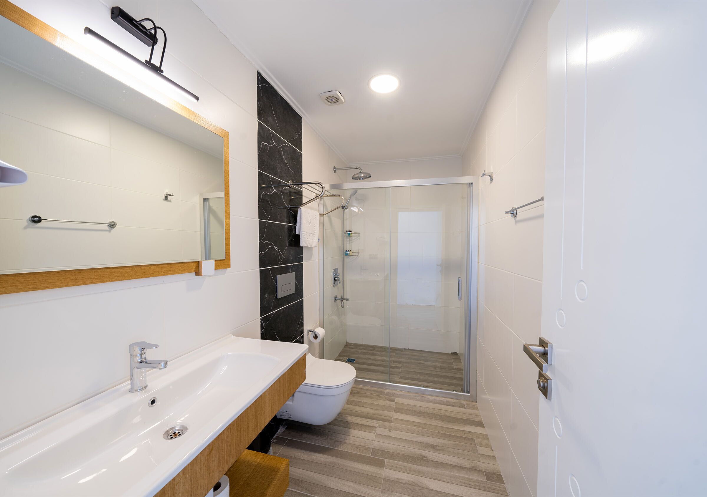 A modern bathroom with a sink, mirror, toilet, and shower.