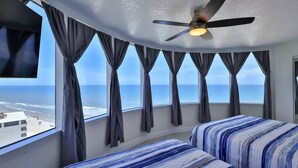 Ein Zimmer mit gewölbter Decke, einem Deckenventilator und einem großen Fenster mit Vorhängen.