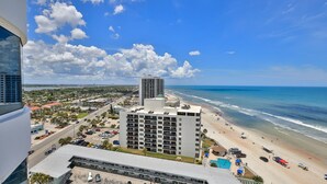 Ein Hochhaus-Hotel mit Blick auf einen Strand und den Ozean, sowie einen Parkplatz.