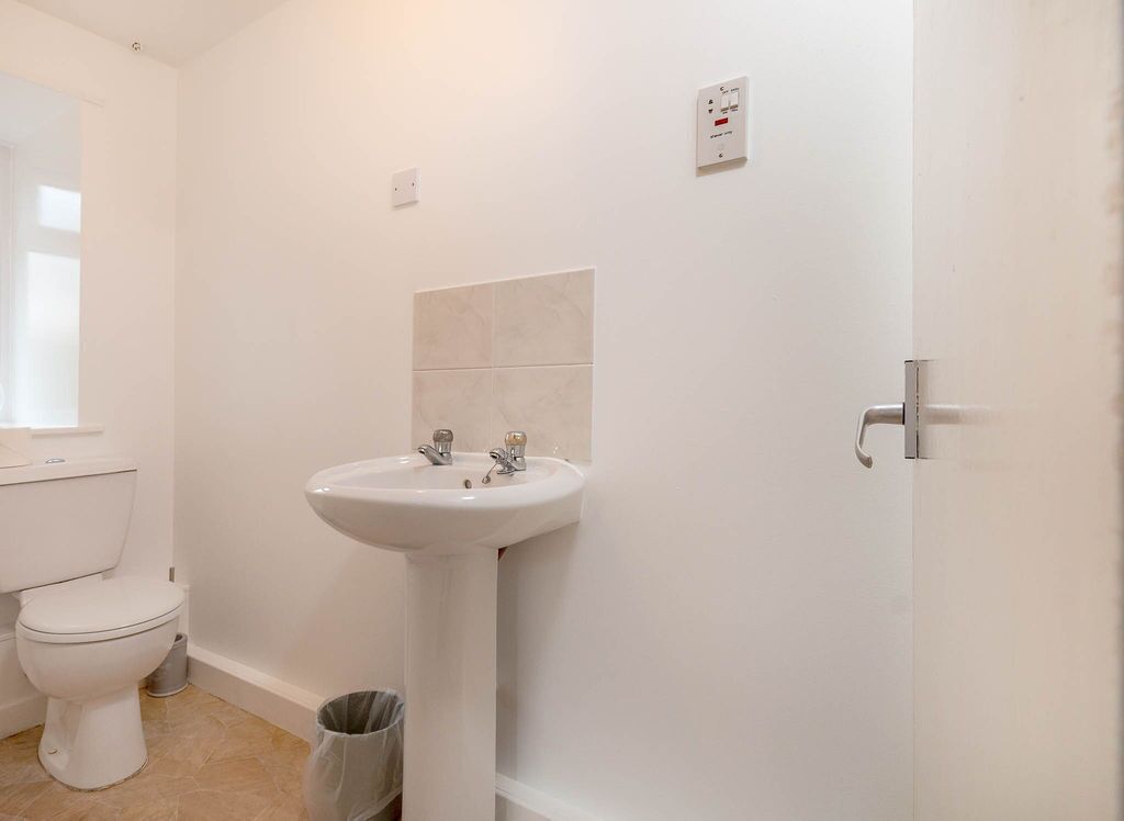 Un baño pequeño y limpio con inodoro, lavabo y cubo de basura.
