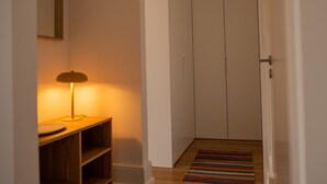 Käytävällä on puinen penkki, lamppu ja raidallinen matto, ja se johtaa ovelle.