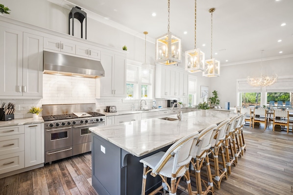 A modern kitchen with white cabinets, stainless steel appliances, and a large island with bar stools.
