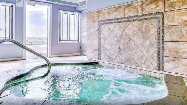 Ett spaområde med ett bubbelbad, en kakelbeklädd vägg och ett fönster med utsikt.