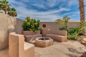 Relax in the serene outdoor patio with seating, a fire pit, and lush greenery.
