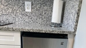 A stainless steel refrigerator with a double door, a granite countertop above, and a white wall with a power outlet. - Cottage totally private detached 1 queen bed private patio (West Palm Beach)