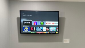 A flat-screen TV mounted on a wall displaying a home screen with various streaming apps and a list of recently used apps. - Cottage totally private detached 1 queen bed private patio (West Palm Beach)