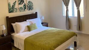 Ein Schlafzimmer mit Bett, Nachttischen, Deckenventilator und Kunstwerken an der Wand.