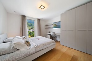 A bedroom with a bed, a desk, and a wardrobe.