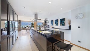 A modern kitchen with a large island, stainless steel appliances, and a view of mountains. - Montreux Panoramic Views 4BD Apartment (Montreux)