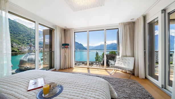 A bedroom with a large bed, a view of a lake, and a balcony with outdoor furniture. - Montreux Panoramic Views 4BD Apartment (Montreux)