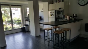 Een moderne keuken met een groot eiland, barkrukken en uitzicht op buiten.