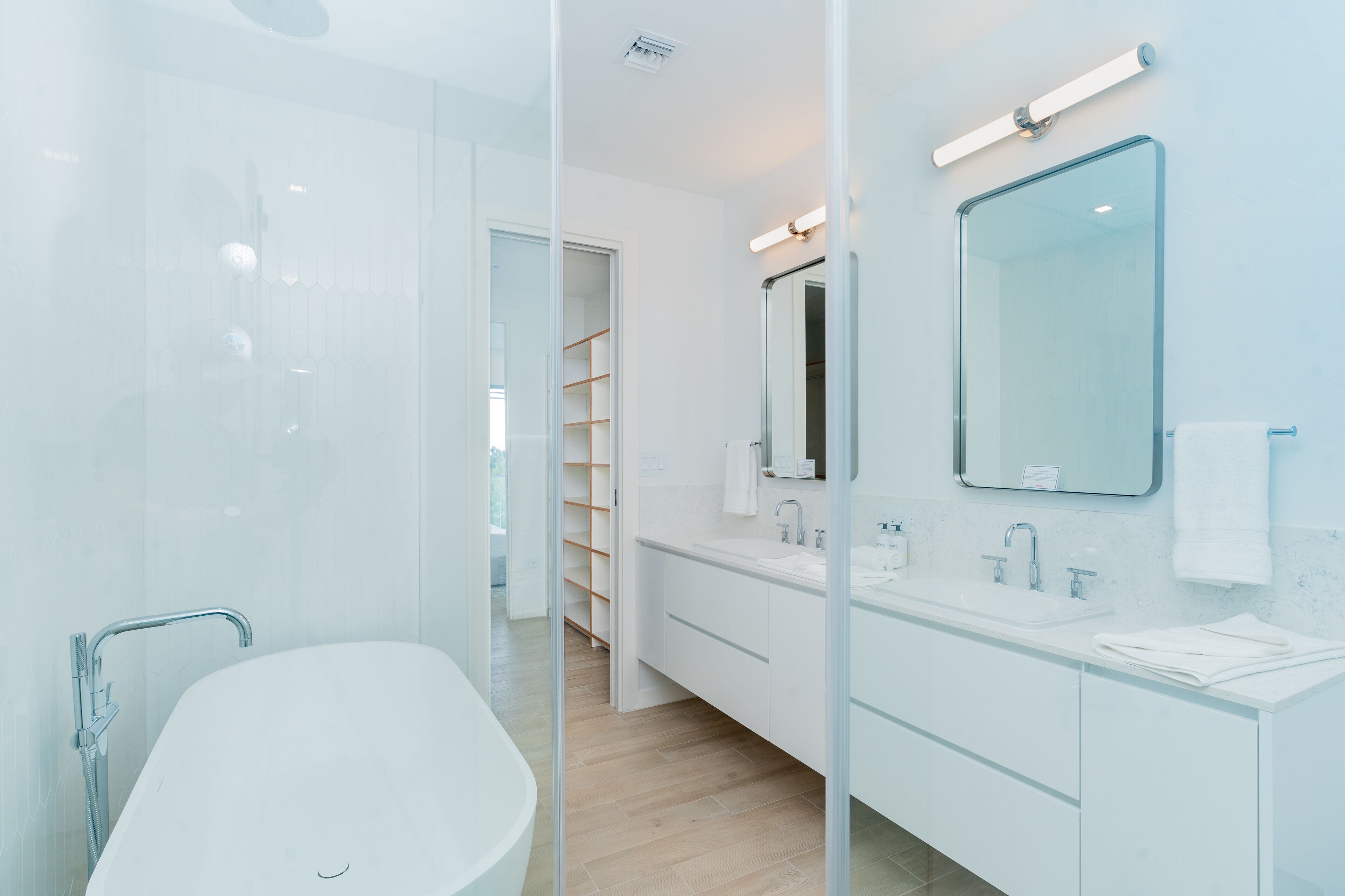A modern bathroom with a glass-enclosed shower, a white sink, and a large mirror.