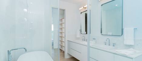 A modern bathroom with a glass-enclosed shower, a white sink, and a large mirror.