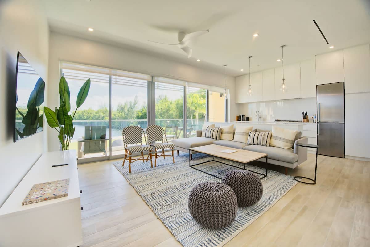 A modern living room with a sofa, chairs, and a coffee table. There is a large window with a view of greenery.