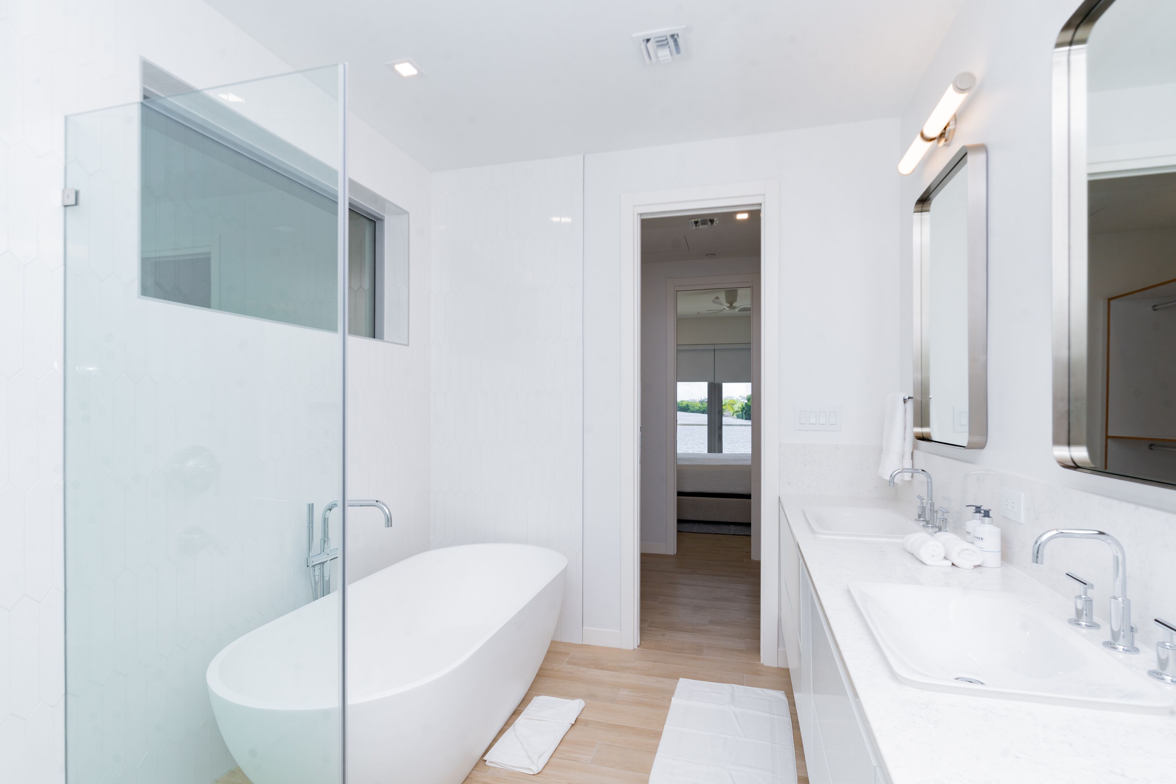 A modern bathroom with a glass-enclosed shower, a freestanding bathtub, and a double sink vanity.