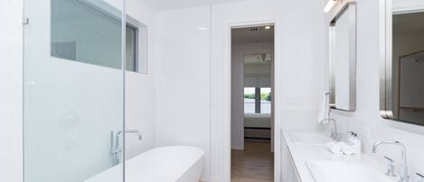 A modern bathroom with a glass-enclosed shower, a freestanding bathtub, and a double sink vanity.