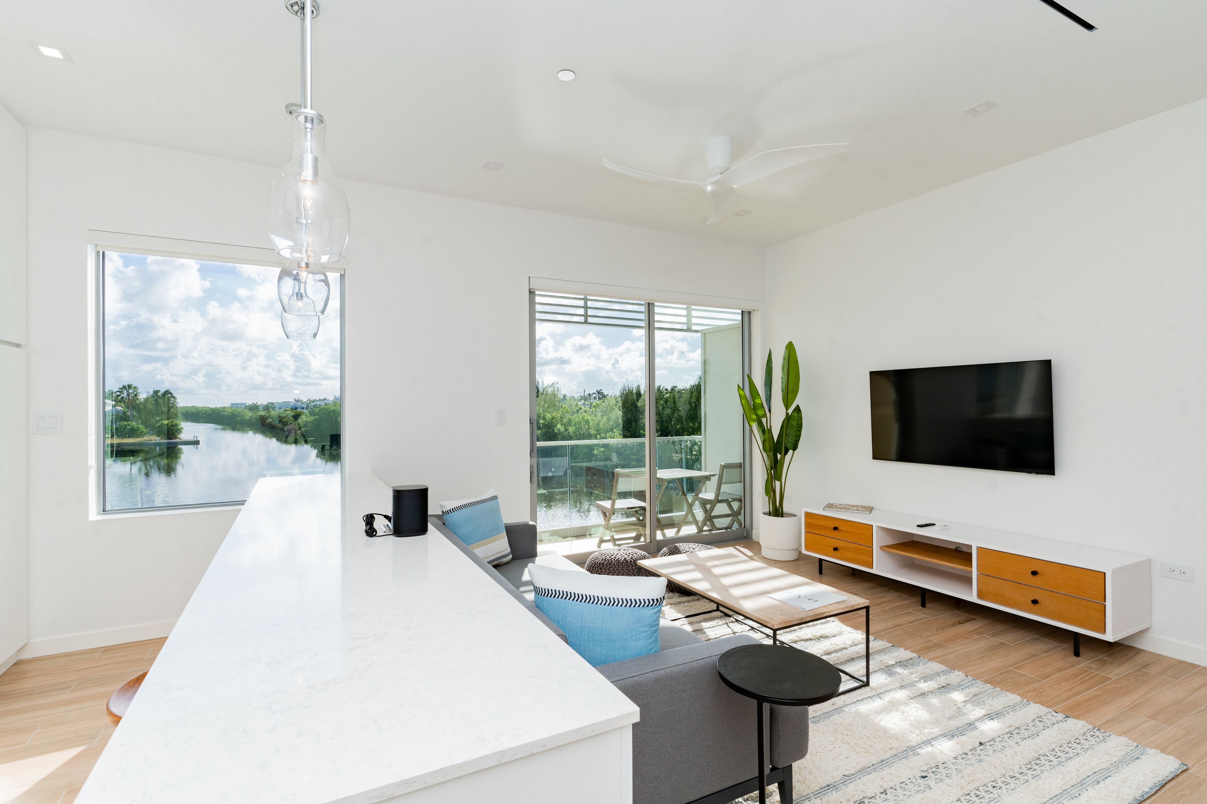 Una cocina moderna con una isla grande, un comedor con vistas a un lago y un televisor montado en la pared.