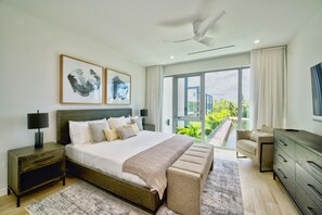 A modern bedroom with a large bed, a bench, a dresser, and a TV.