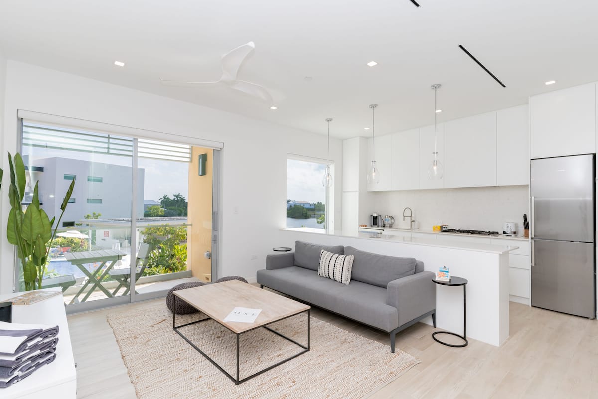 A modern apartment with a living area, kitchen, and balcony with a view.