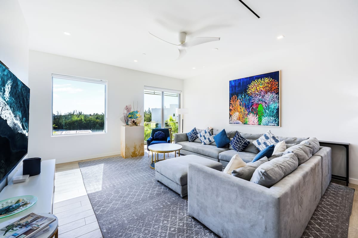 A modern living room with a grey sofa, a coffee table, and a large painting on the wall.