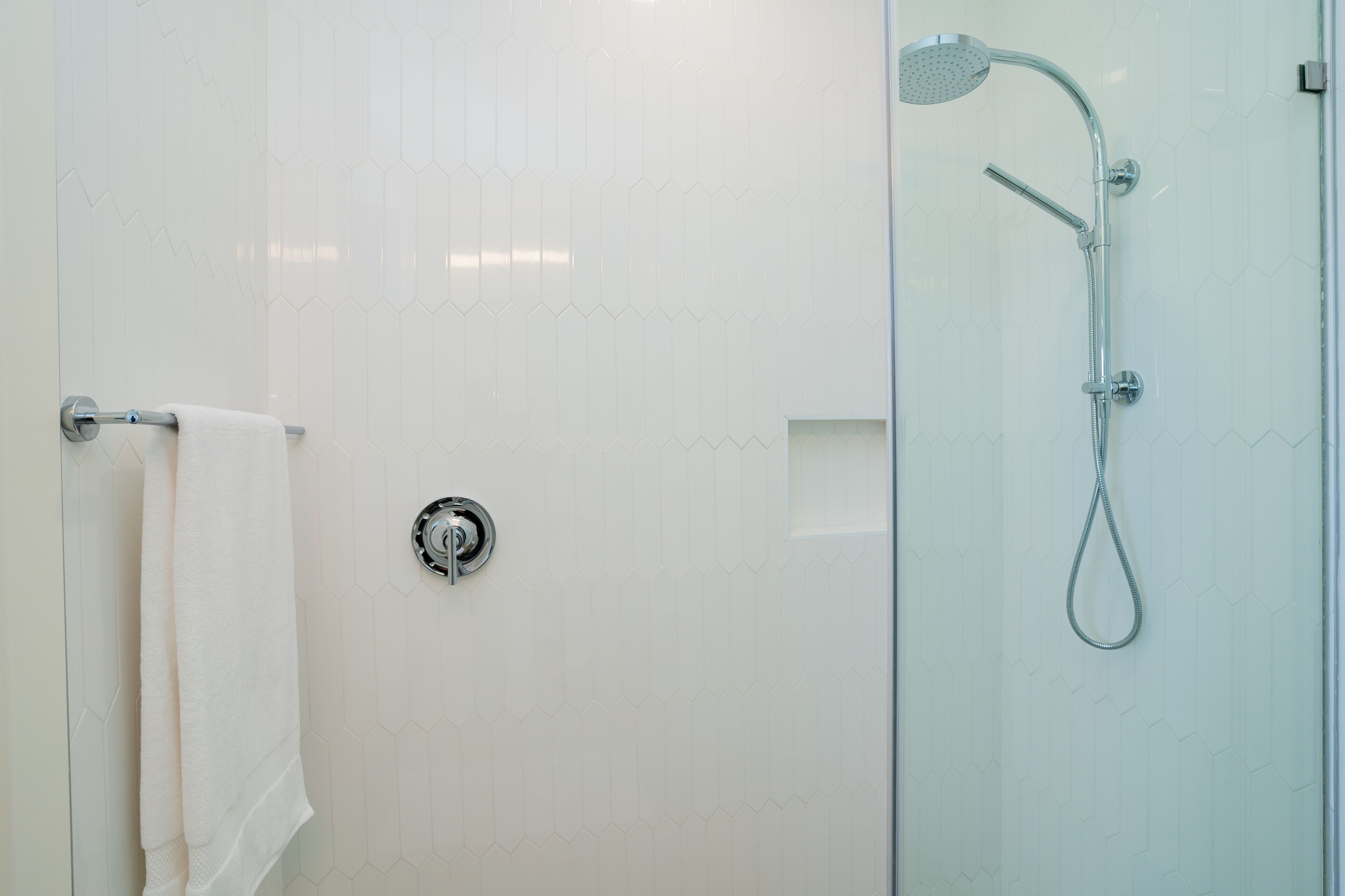 Un baño moderno con cabina de ducha de vidrio, un perchero y un cabezal de ducha visible.