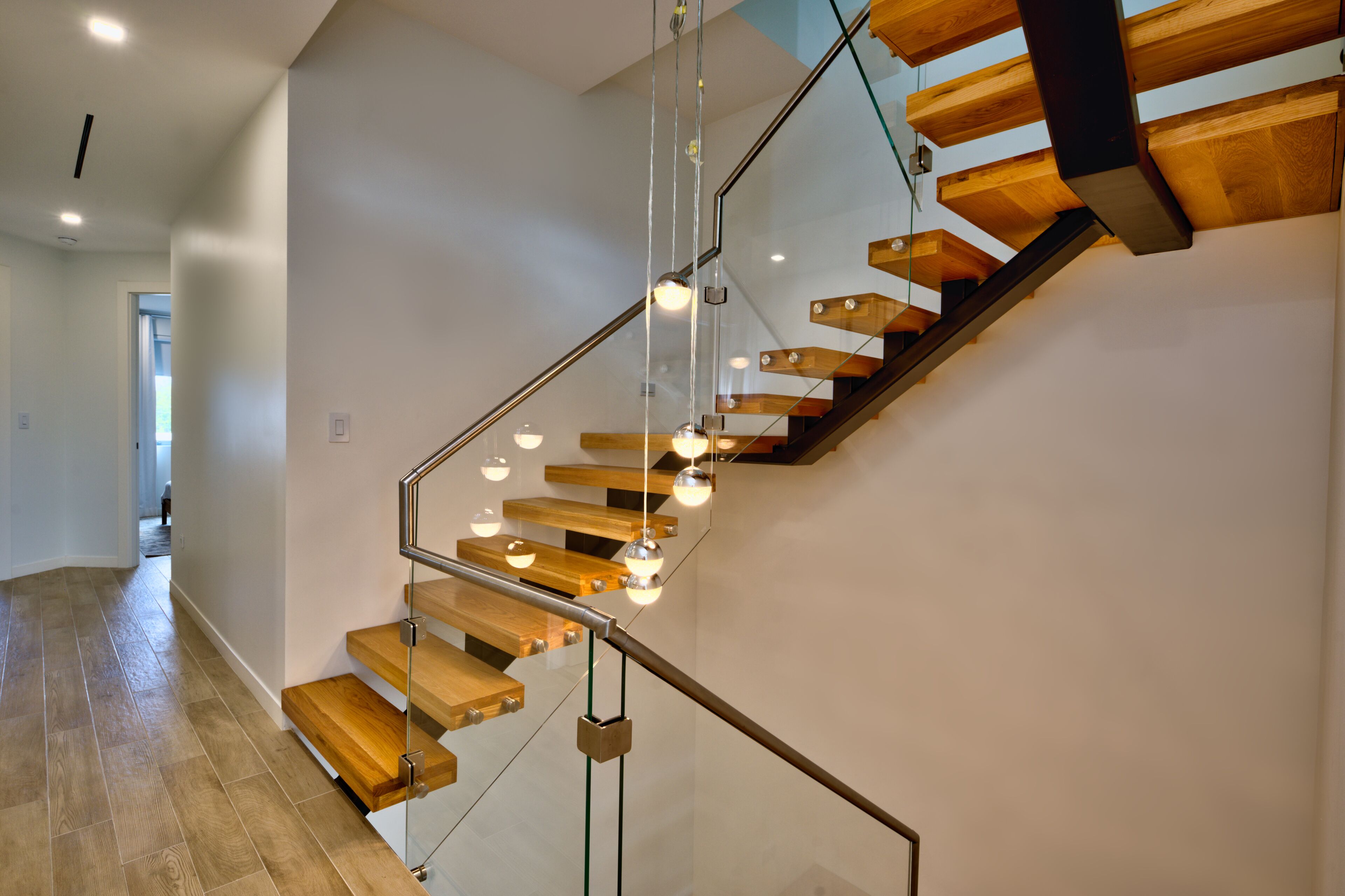 A modern staircase with wooden steps and glass railings, leading to an upper floor.