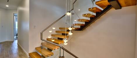 A modern staircase with wooden steps and glass railings, leading to an upper floor.
