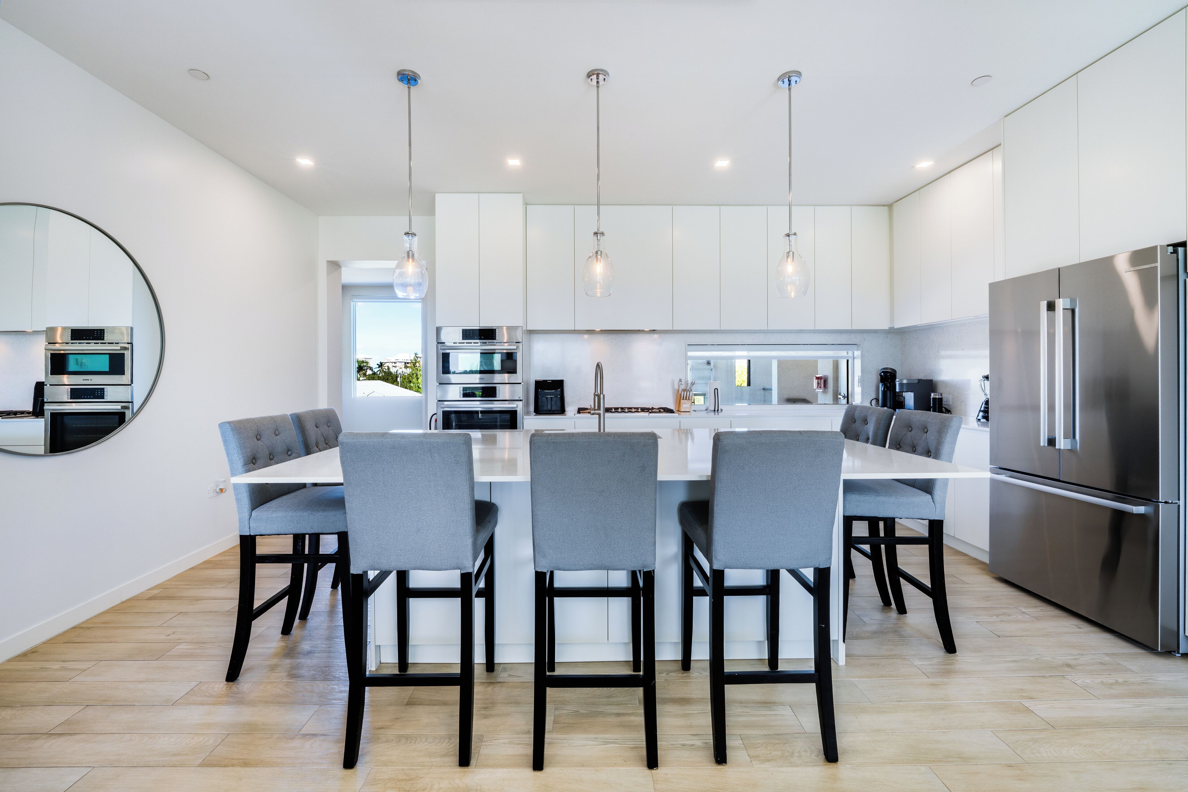 Una cocina moderna con una isla central, electrodomésticos de acero inoxidable e iluminación colgante.