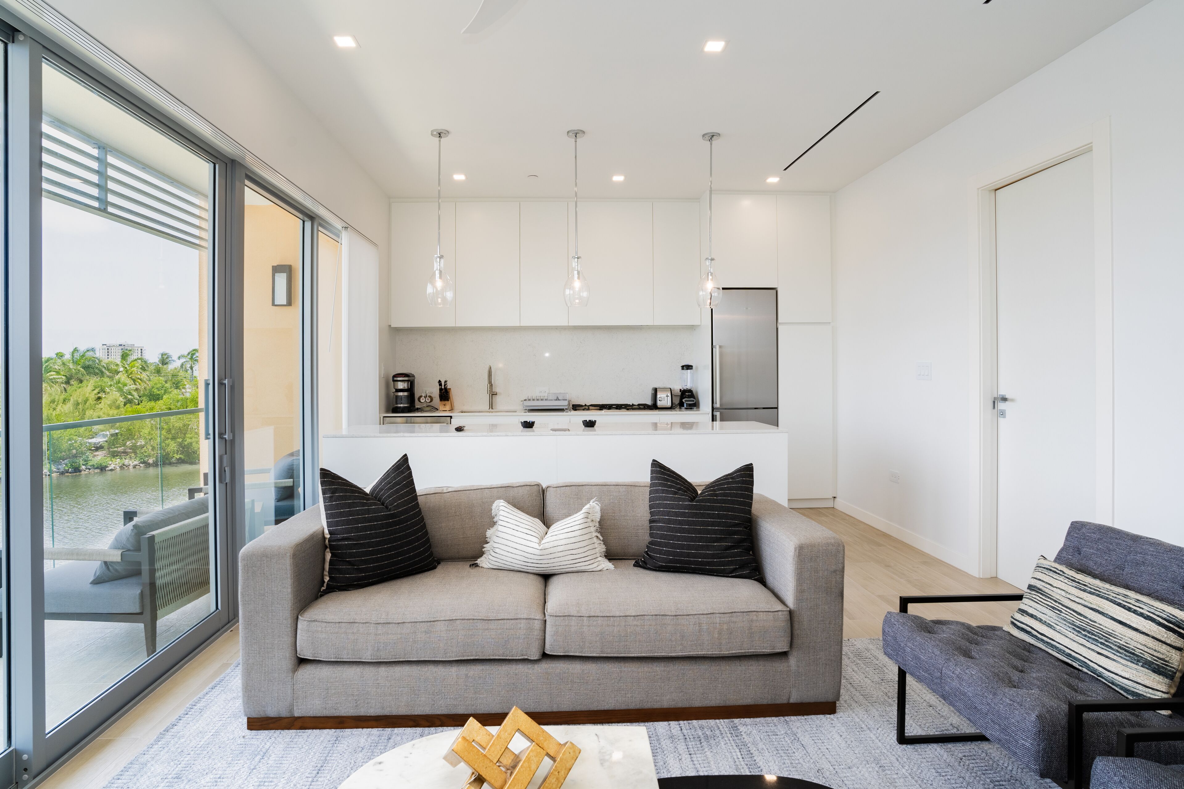 A modern living room with a sofa, a coffee table, and a view of the kitchen.