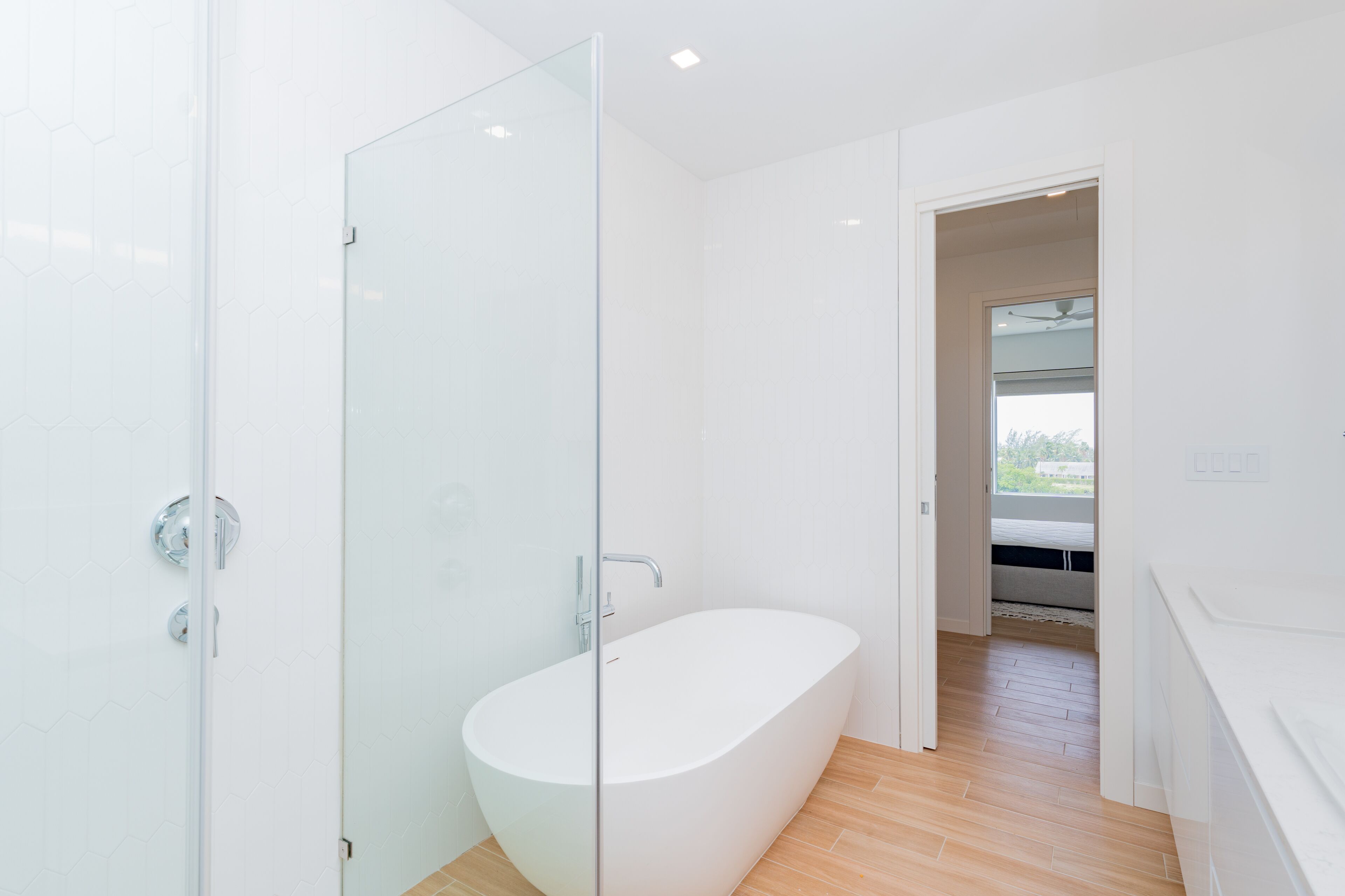 Une salle de bain moderne avec une douche à l’italienne en verre, une baignoire sur pieds et un plancher en bois.