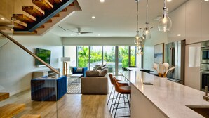 A modern kitchen with a marble countertop, stainless steel appliances, and a large window overlooking greenery. - ONE Canal Point (Seven Mile Beach)