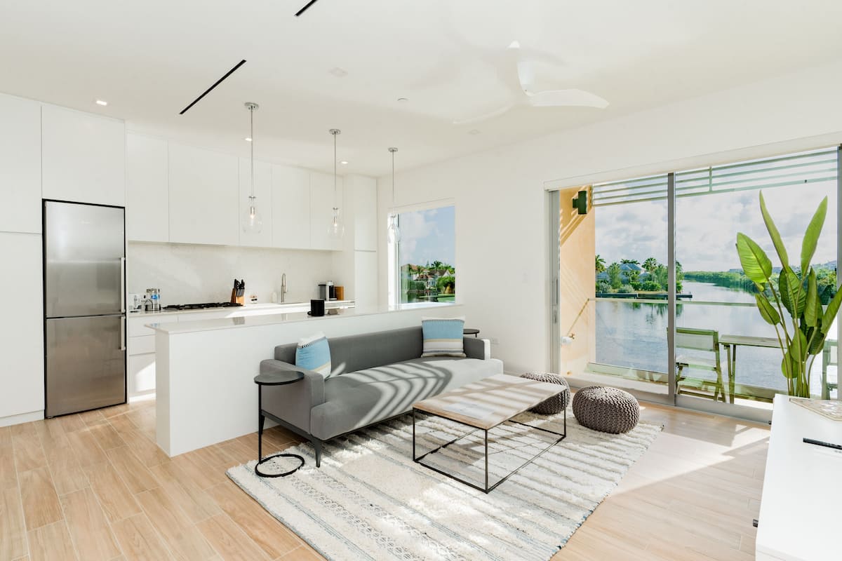 A modern kitchen with white cabinets, a stainless steel refrigerator, and a large island with seating.
