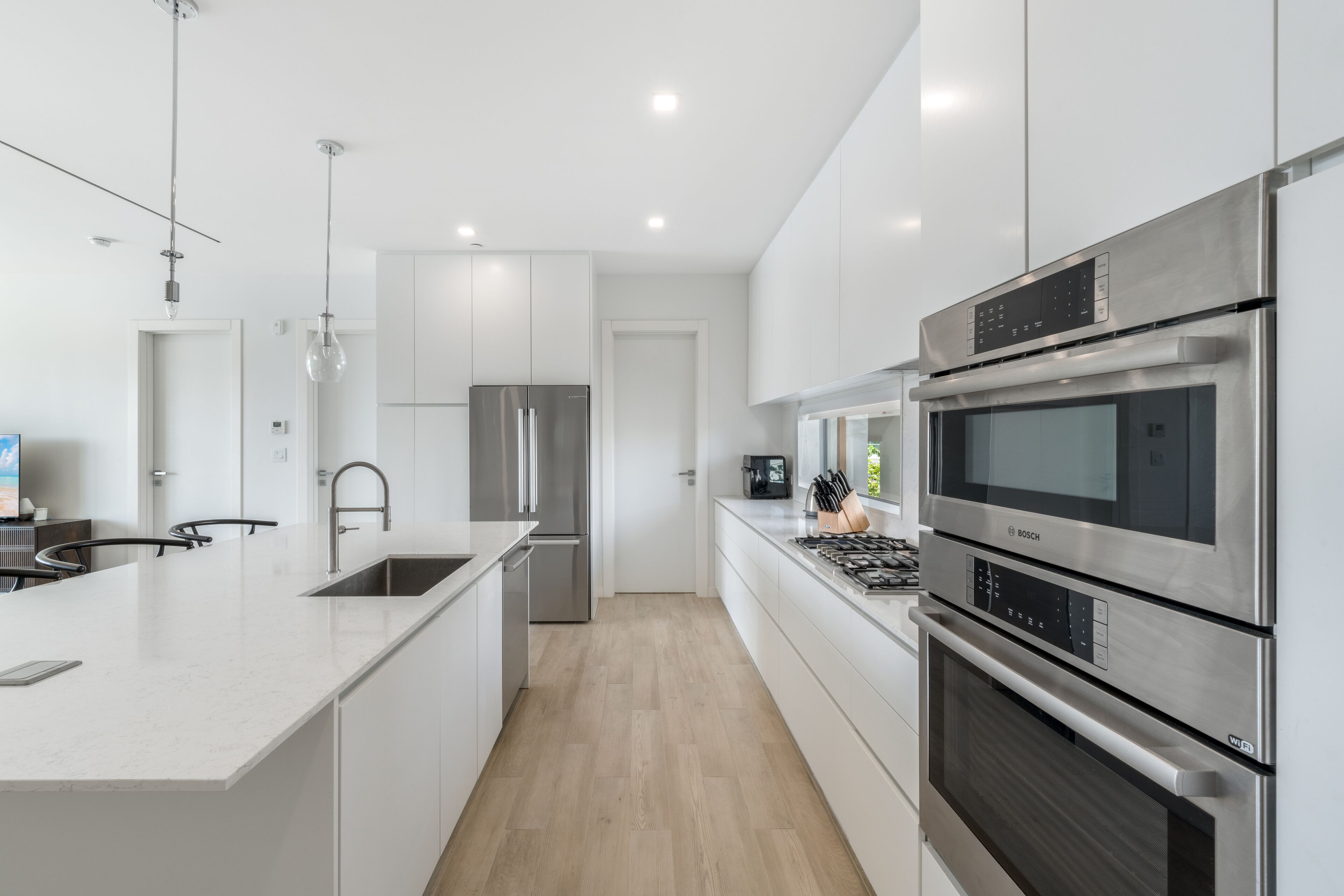 Una cocina moderna con armarios blancos, electrodomésticos de acero inoxidable y una isla central.