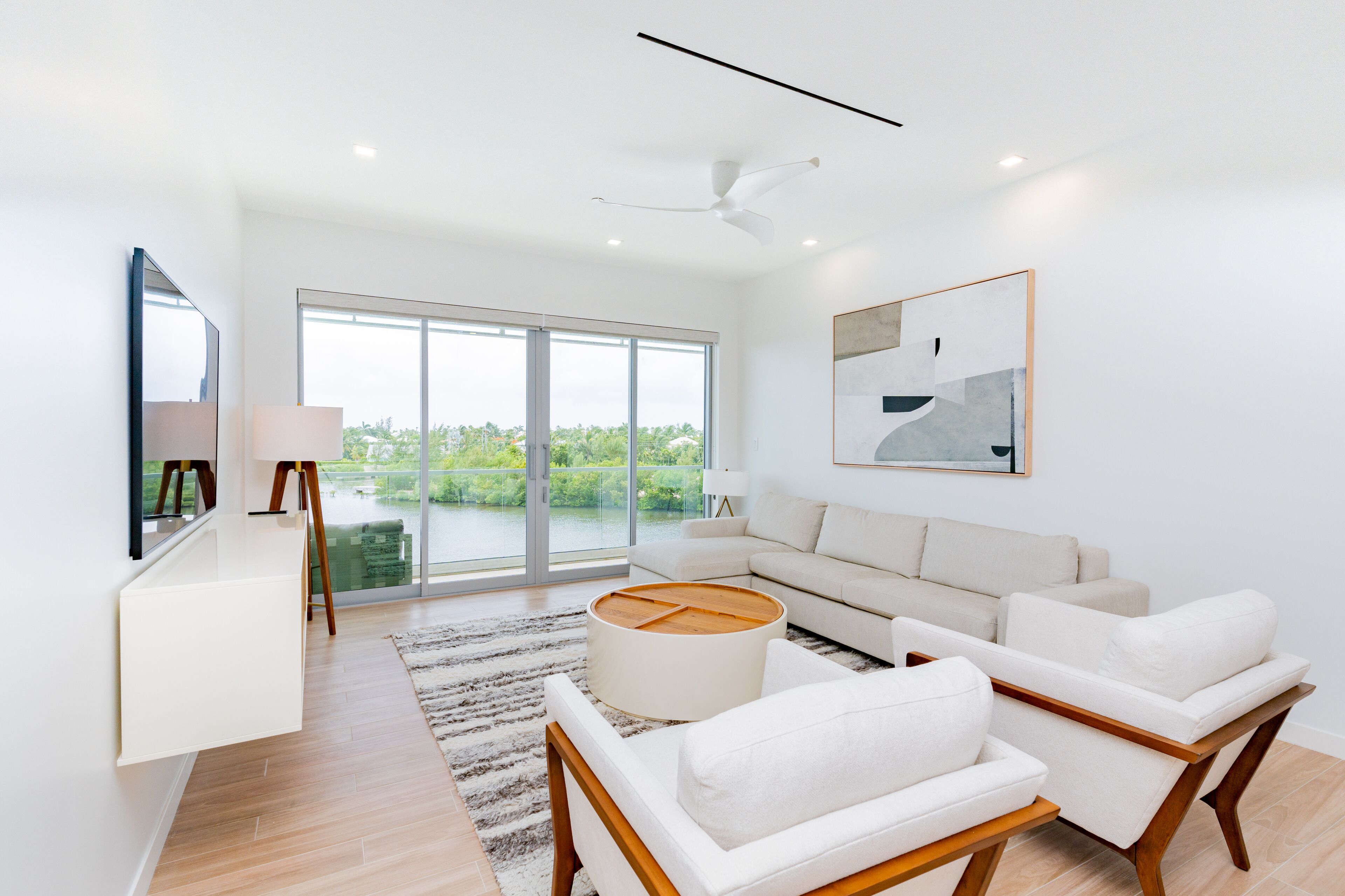 Un salón amplio con un ventanal grande, un ventilador de techo y un sofá moderno.