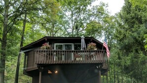 Eine Hütte mit Balkon, umgeben von Bäumen.