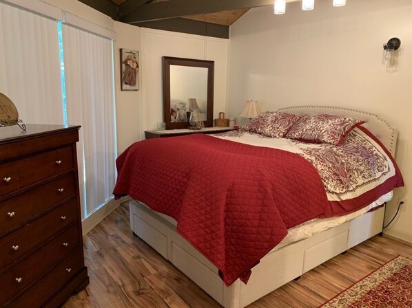 A bedroom with a bed, dresser, mirror, and a window with blinds.