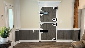 A spacious room with a wooden floor, a ceiling fan, a door with a decorative handle, and a brown leather couch. - Blue Tranquility at Lake Gaston (Littleton)
